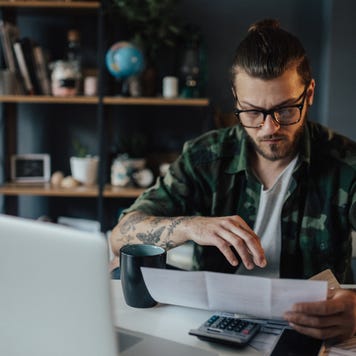 Young man calculates finances at a table