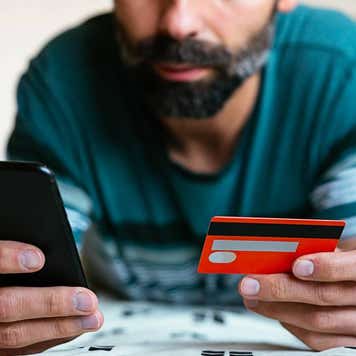 Close up hand holding credit card and shopping online on bed