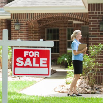 Real estate agent greets a client in front of a red brick home