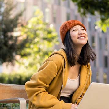 Asian female using laptop outside university in campus