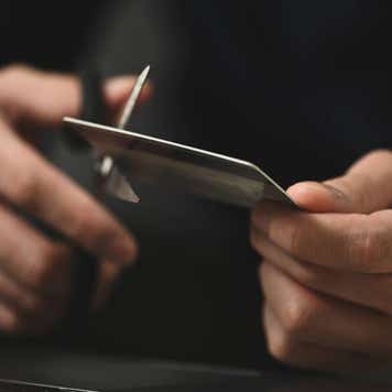 Young man cutting credit card with scissors