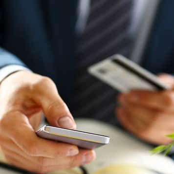 Male arms in suit hold credit card and phone