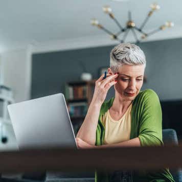 Businesswoman using laptop and documents, drinking coffee. Looking concentrated