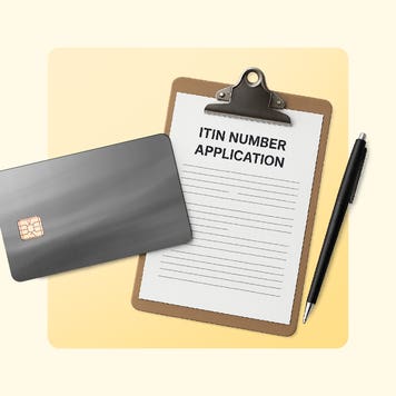 An ITIN number application on a clipboard next to a black pen and black credit card