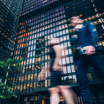 Two business people walking on downtown street. Blurred motion effect.