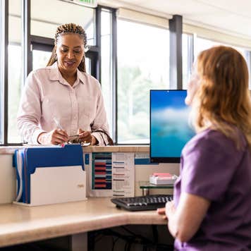 Female patient paying with credit card at doctor's office front desk