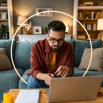Man sitting on couch and leaning over laptop and doing some work