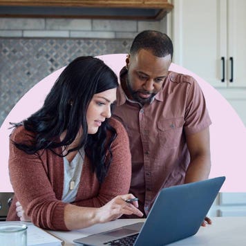 Man and woman standing at kitchen counter looking at laptop