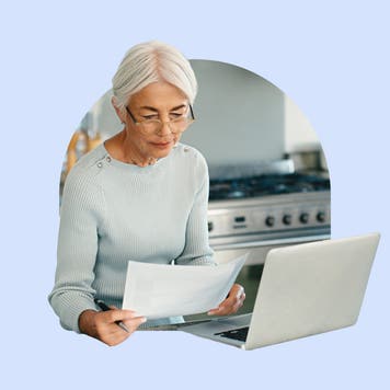 Older woman in glasses looking a her life insurance policy by a computer