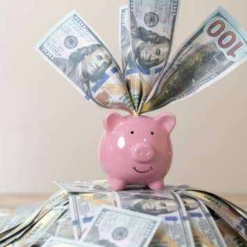 Pink piggy bank stuffed with dollar bills
