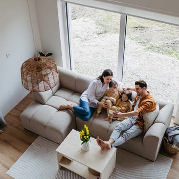 A top view of a young family sitting on a couch in their new home