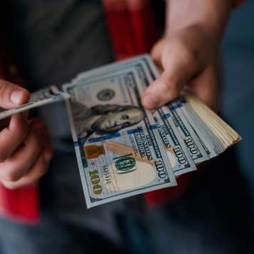 Man holds $100 bills and a credit card