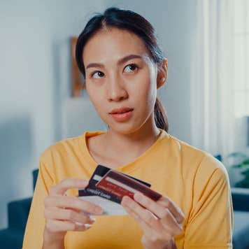 Young woman holding a stack of cards and thinking