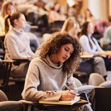 A young woman takes an exam in a college lecture hall.