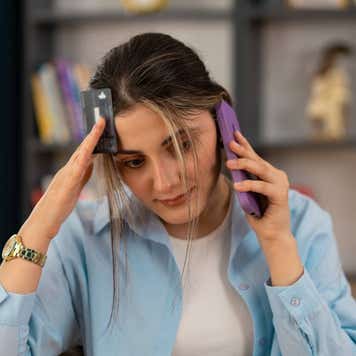 person holding phone and debit card and appears stressed