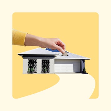 Concept of a home as a piggy bank with a hand inserting money