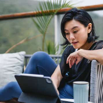 person looking at computer while sitting on balcony