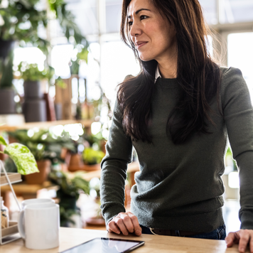 Flower shop owner using digital tablet at counter.