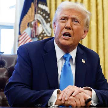 Donald Trump sitting at a desk in the Oval Office.