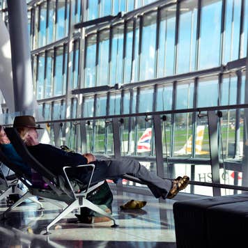 Travelers sit at airport gate looking out windows