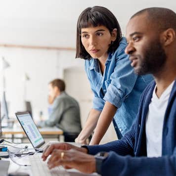 man and woman working together at a computer in an office