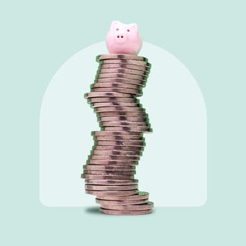 A piggybank resting atop a stack of coins on a green background.