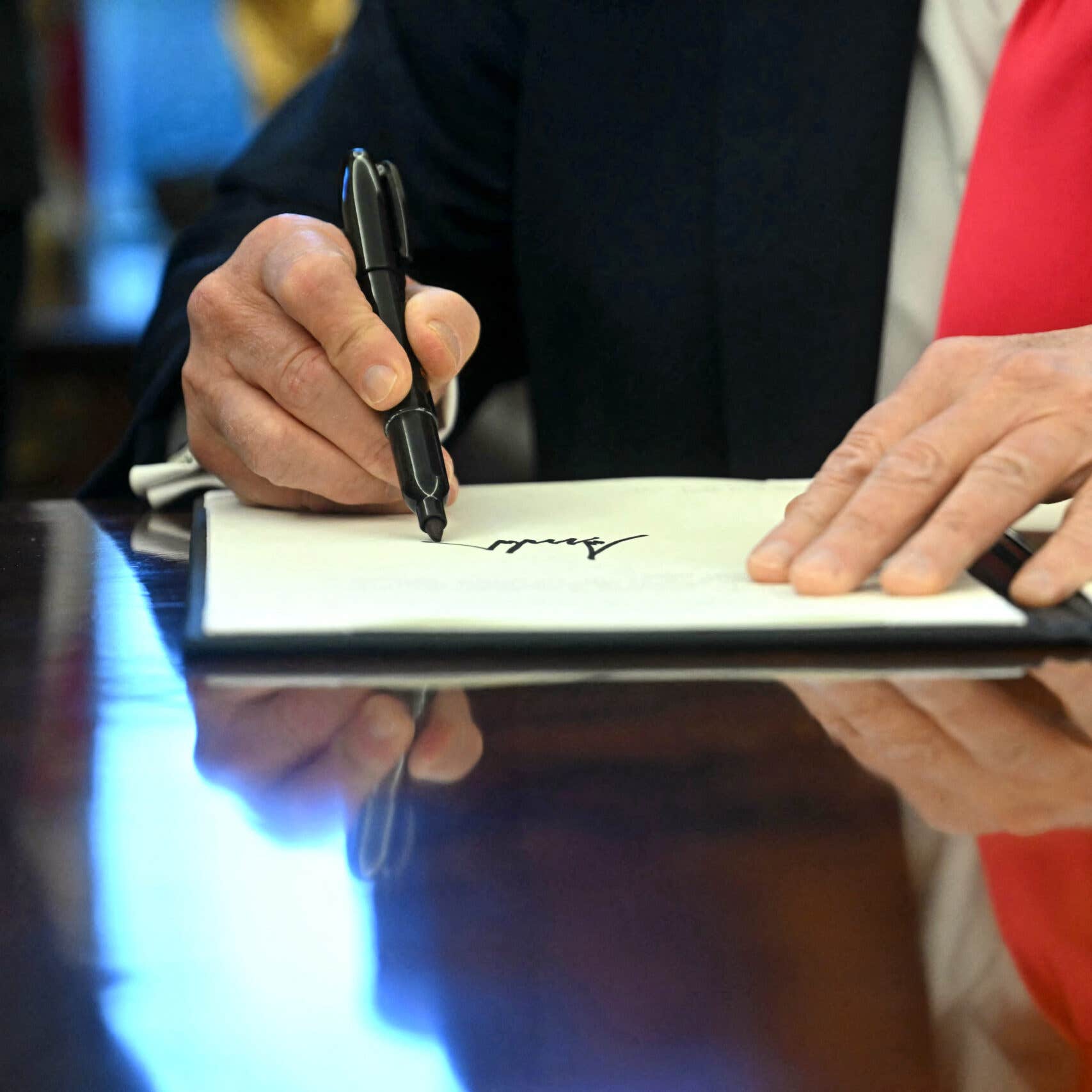 Close up of hands as Donald Trump signs executive order.