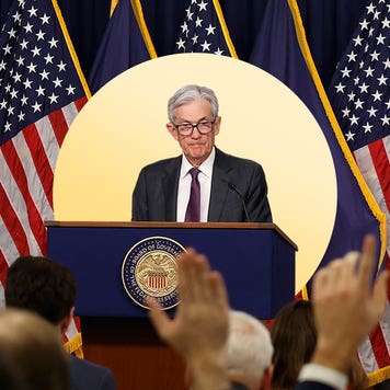 Image of Jerome Powell standing behind a podium with American flags behind him.