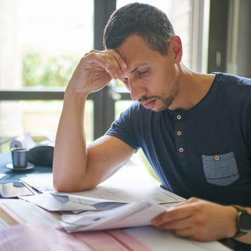 Man sits at a table reviewing a large array of paperwork.