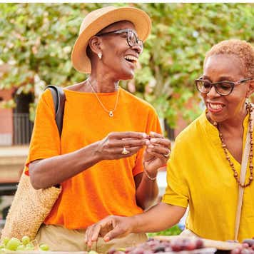 Two retirement-age women shop at a farmer's market.