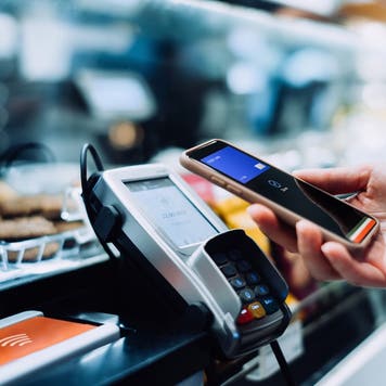 Close up of a woman's hand paying with her smartphone in a cafe