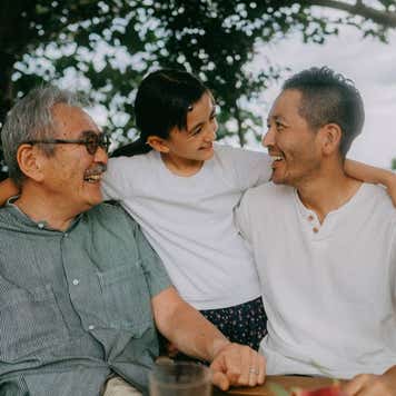 Three generations of a family smile at each other outside.