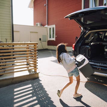 woman lifting cooler into black car