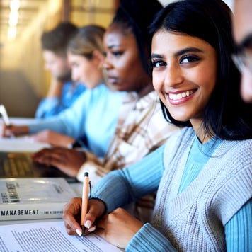 College student writing notes for business management in classroom, course and campus. Portrait, young indian girl and university student happy for learning, education and studying at finance academy - stock photo