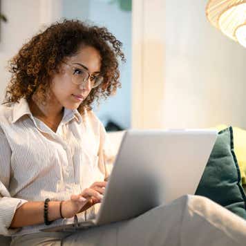 Woman sitting on her couch, looking at her laptop