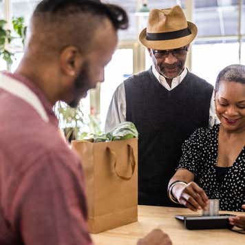 Couple making a purchase at flower shop counter with credit card