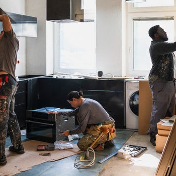 Three adults working on remodeling a kitchen.