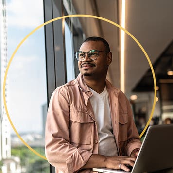 Person sitting at desk working on laptop with design element in the background