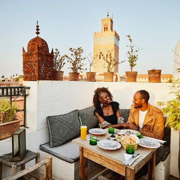 Wide shot of smiling couple dining at rooftop restaurant in the Medina of Marrakech while on vacation