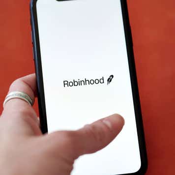 A hand holding a phone with the Robinhood logo on it.