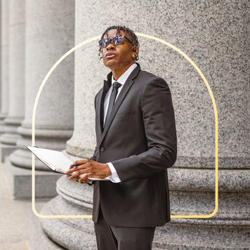 A Black man stands in front of a column