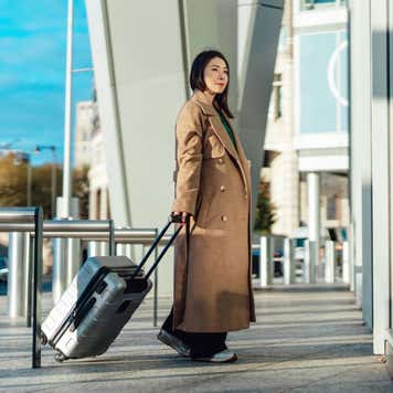 Young Asian business woman with suitcase arriving airport