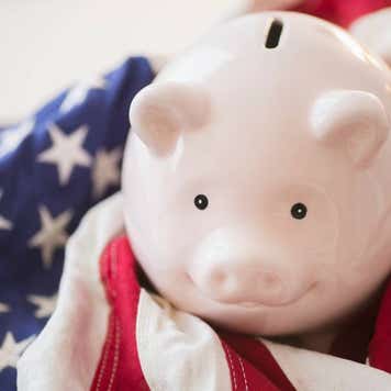A smiling pink piggy bank resting atop a U.S. flag
