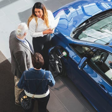 High angle view of saleswoman showing car to customers at showroom