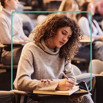 A woman takes notes in college.