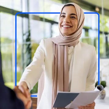 Woman shakes a hand during a job interview with a blue illustrated square.