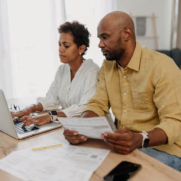 A couple is deeply involved in their financial planning as they work together, using a laptop, and reviewing various documents.