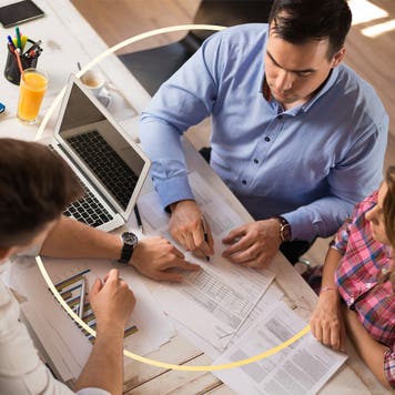 A couple sits across a desk from a banker, reviewing financial documents