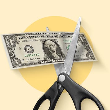 Image of a pair of open scissors with a U.S. dollar bill lying between the blades ready to be cut.