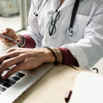 close-up of a female doctor using computer and smartphone